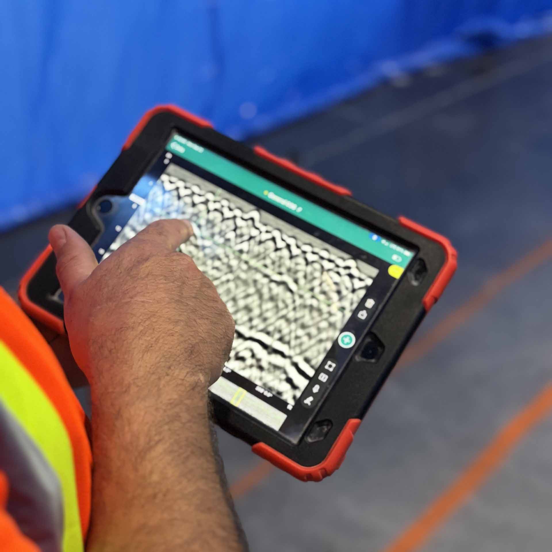 Canadian Cutting & Coring technician running a GPR scanner across a concrete slab and reading the results on the display