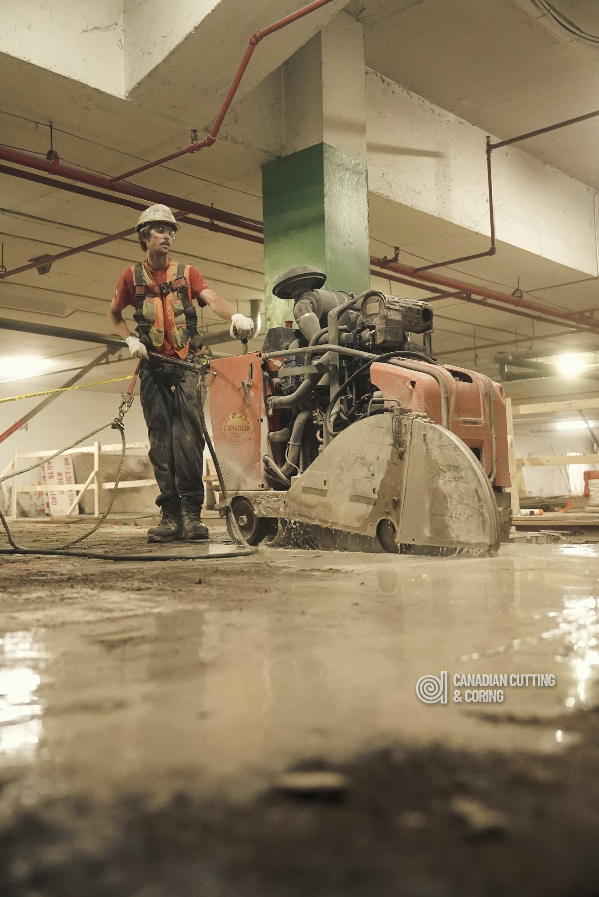 Operator running a high-horsepower diesel flat saw through a reinforced concrete slab in a parking structure