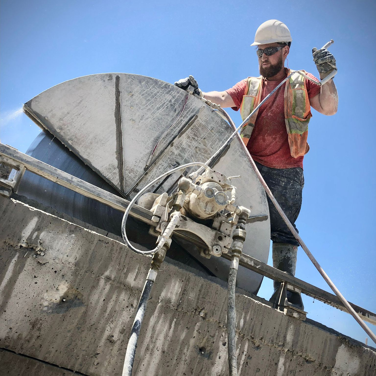 Track-mounted wall saw cutting a vertical opening in a reinforced concrete wall